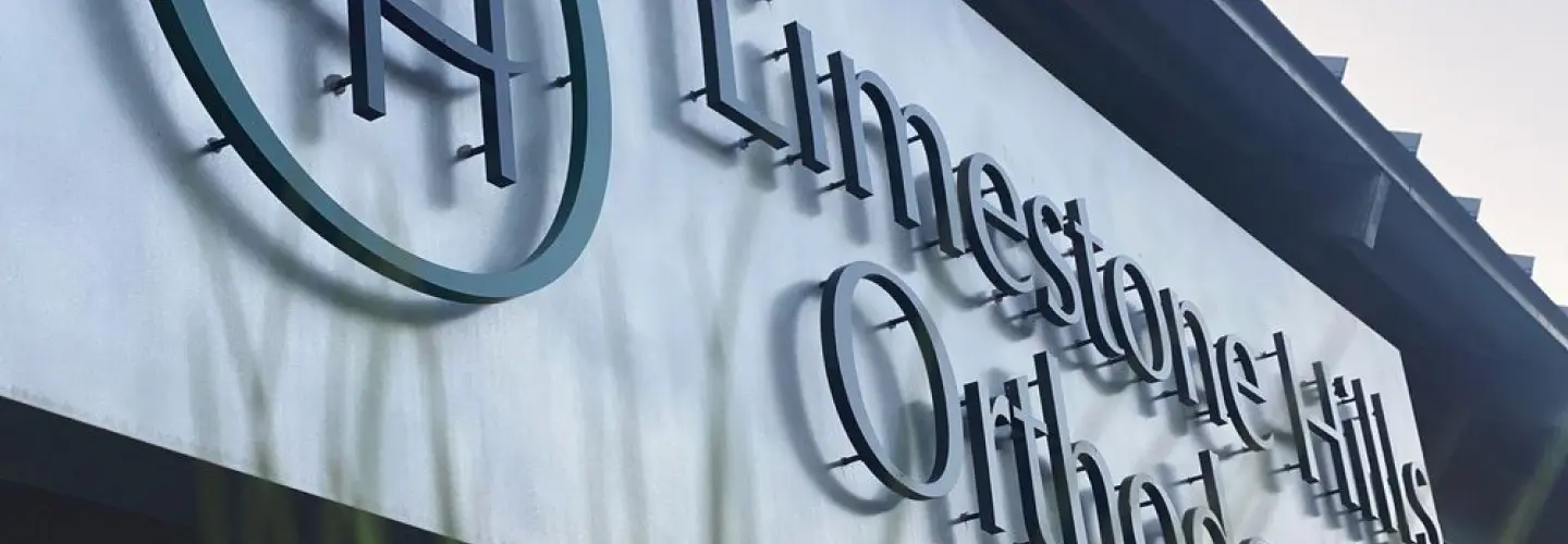limestone hills ortho Exterior signage of Limestone Hills Orthodontics Austin TX, showing the clinic's name and circular logo mounted on a metallic facade.