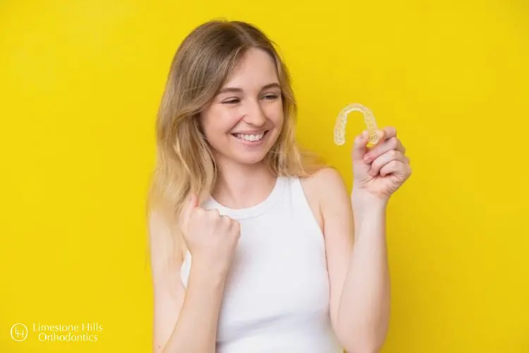 a woman holding an Invisalign. Can Invisalign Fix Overbite?