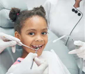 Young girl smiling during a dental examination with orthodontic tools, assisted by dental professionals at Limestone Hills Orthodontics in Austin, TX.