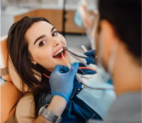 Young woman receiving a dental check-up and cleaning from a gloved dentist at Limestone Hills Orthodontics in Austin, TX.