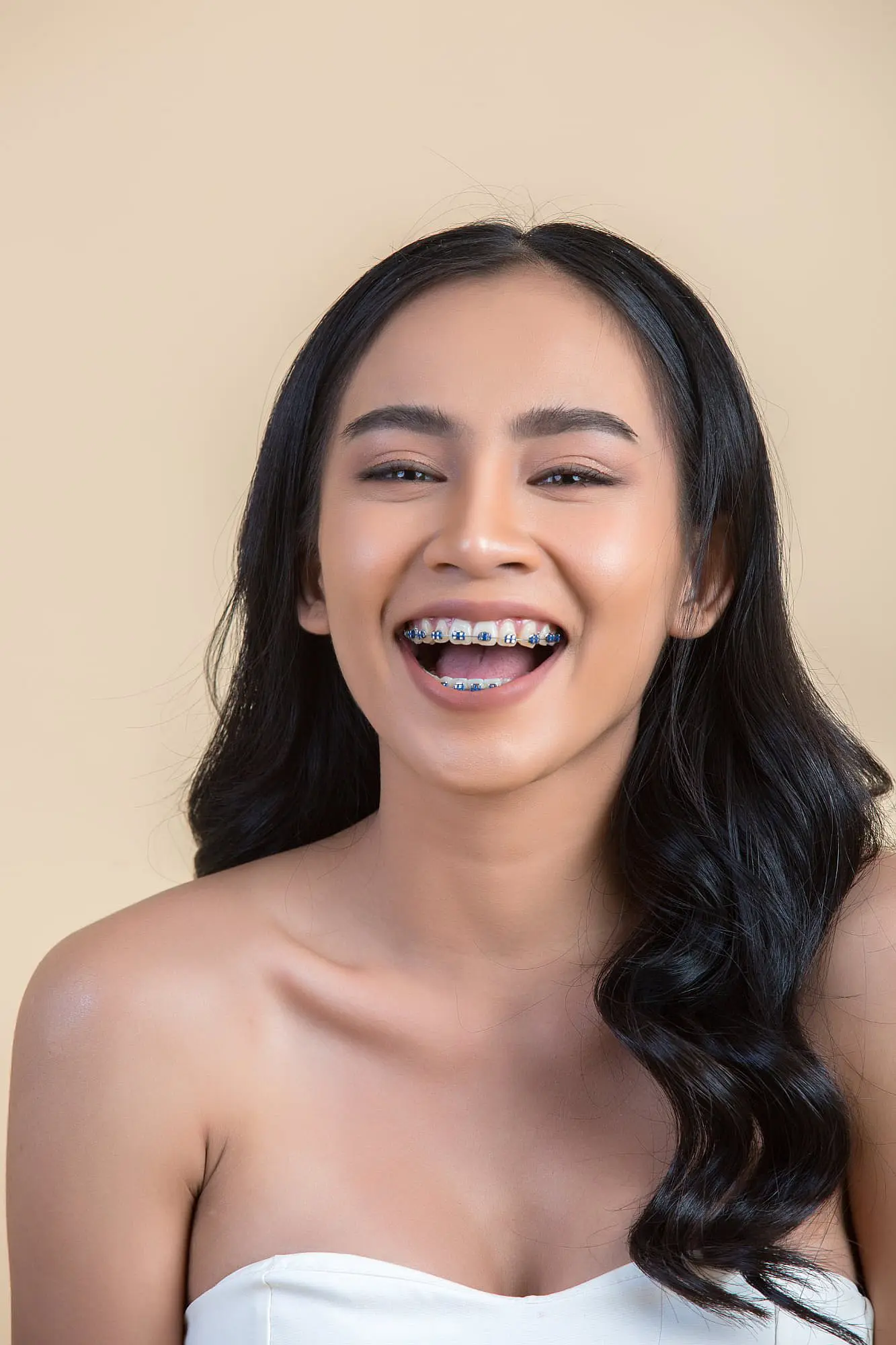 A smiling young woman, who appears to be of Southeast Asian descent based on her features and complexion, shows her braces. Limestone Hills Orthodontics in Austin, TX, offers quality care.