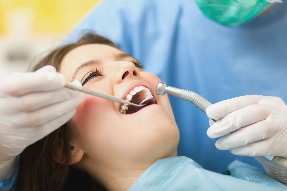 Orthodontist caring for a female patient during a dental procedure after she knows how to speed up orthodontic treatment