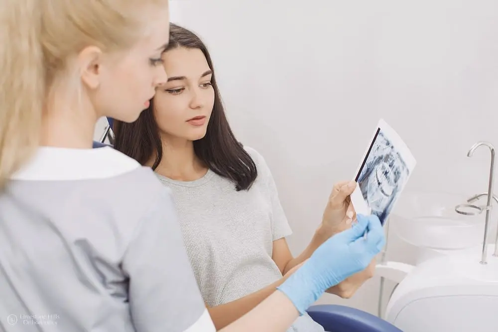 Dentist showing an X-ray image to a patient for consultation after knowing the answer to "Do I Still Need to See a Dentist During Orthodontic Treatment?"