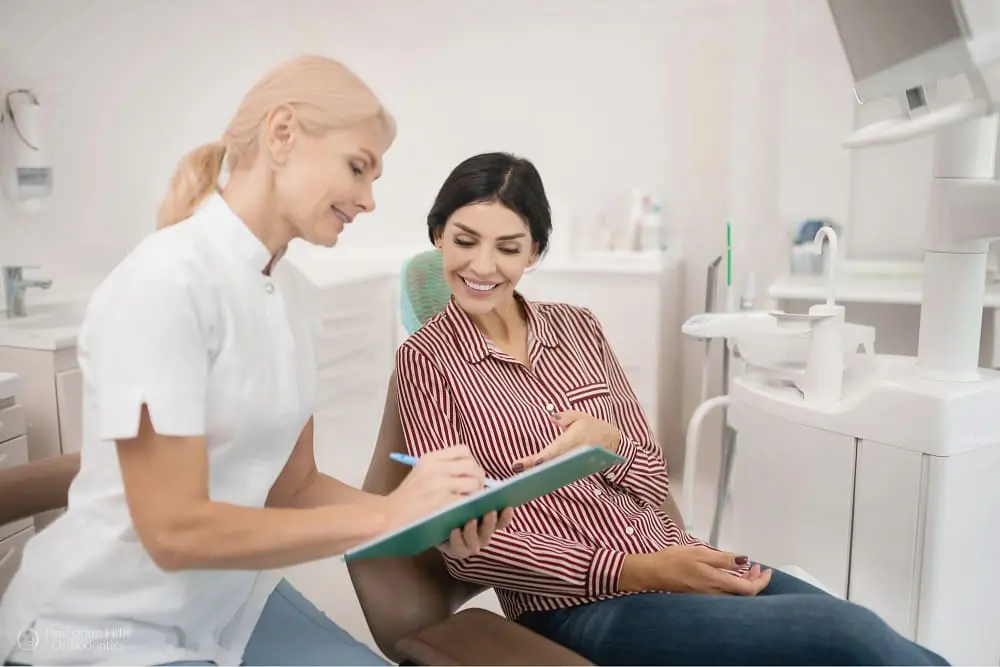 Patient discussing her dental treatment with an orthodontist in a bright clinic as one of the orthodontic consultation process