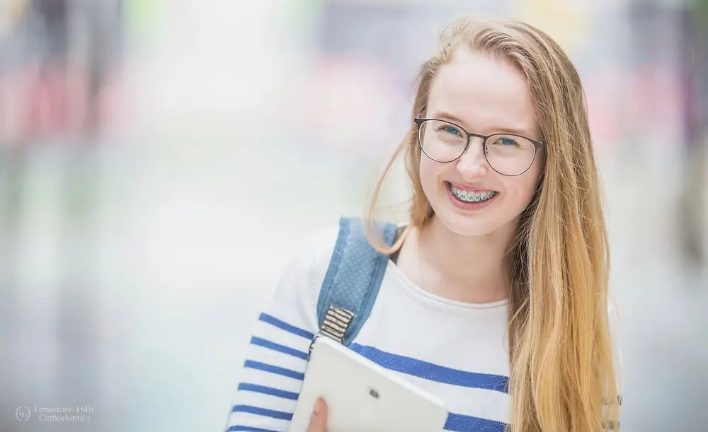 Portrait of a smiling, beautiful teenage school girl being back to school with braces, outdoors with blurred background