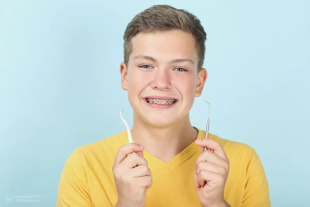 Young man with metal braces holding a toothbrush and dentist tool after knowing about remove food from braces