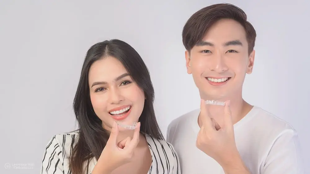 Young smiling man and woman holding Invisalign clear aligners together after discussing about tips to avoid Invisalign irritation