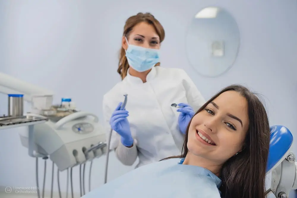 Young female patient sitting in an orthodontist's office, smiling as she receives treatment after Choosing the Best Orthodontic Treatment.