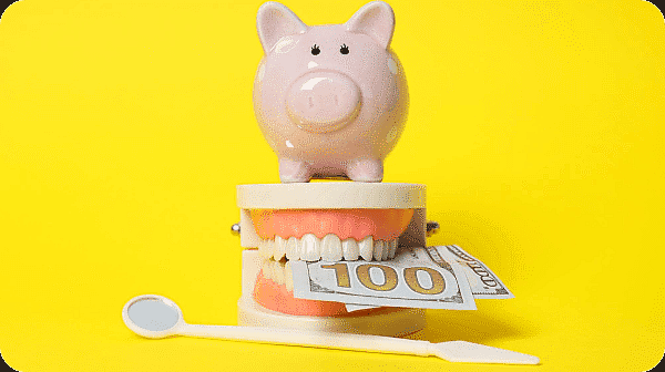 Piggy bank on dental model with $100 bill and dental mirror, illustrating Spirit orthodontic insurance costs at Limestone Hills Orthodontics in Austin, TX.