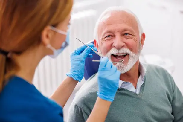 Dentist examining an older male patient during a consultation about Dietary Restrictions and Oral Hygiene During Recovery after Jaw Surgery at Limestone Hills Orthodontics in Austin, TX.