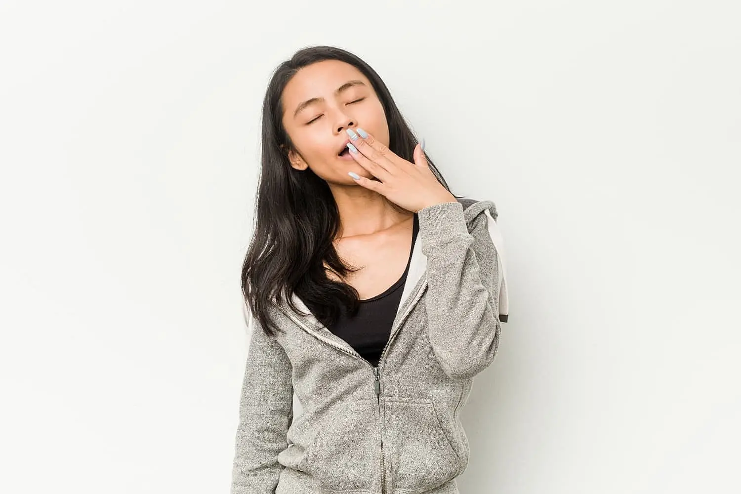 Woman yawning with hand covering mouth, illustrating mouth breathing issue. Limestone Hills Orthodontics in Austin, TX provides treatment and information on mouth breathing causes.