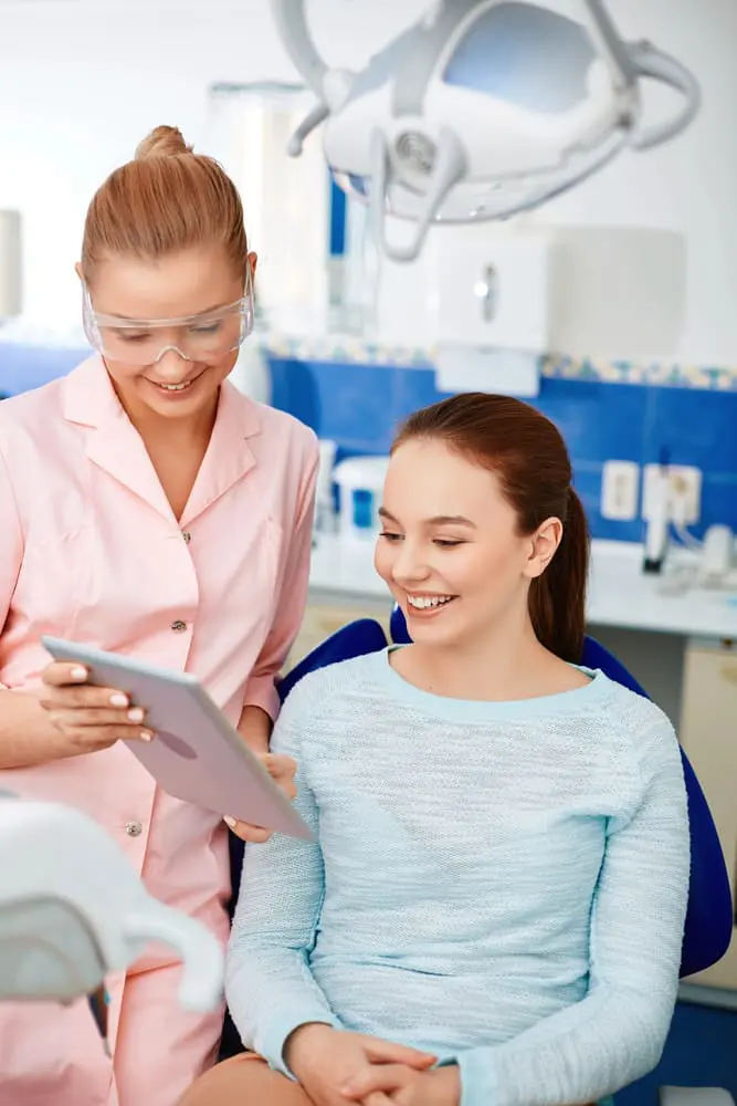 Orthodontist showing a tablet to a smiling adult patient, comparing Invisalign vs braces. Limestone Hills Orthodontics, Austin TX.