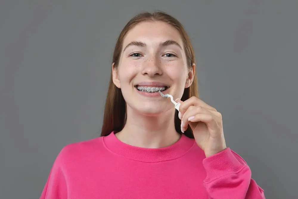 Teenage girl cleaning metal braces with interdental brush, addressing myths about brackets. Limestone Hills Orthodontics, Austin TX.